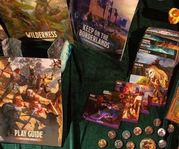 A collection of game boards, booklets, and monster tokens on a dark blue cloth table.